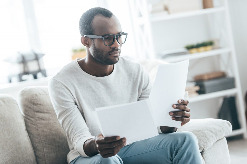Um homem observa atentamente informações em folhas de papel