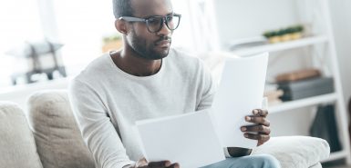 Um homem observa atentamente informações em folhas de papel