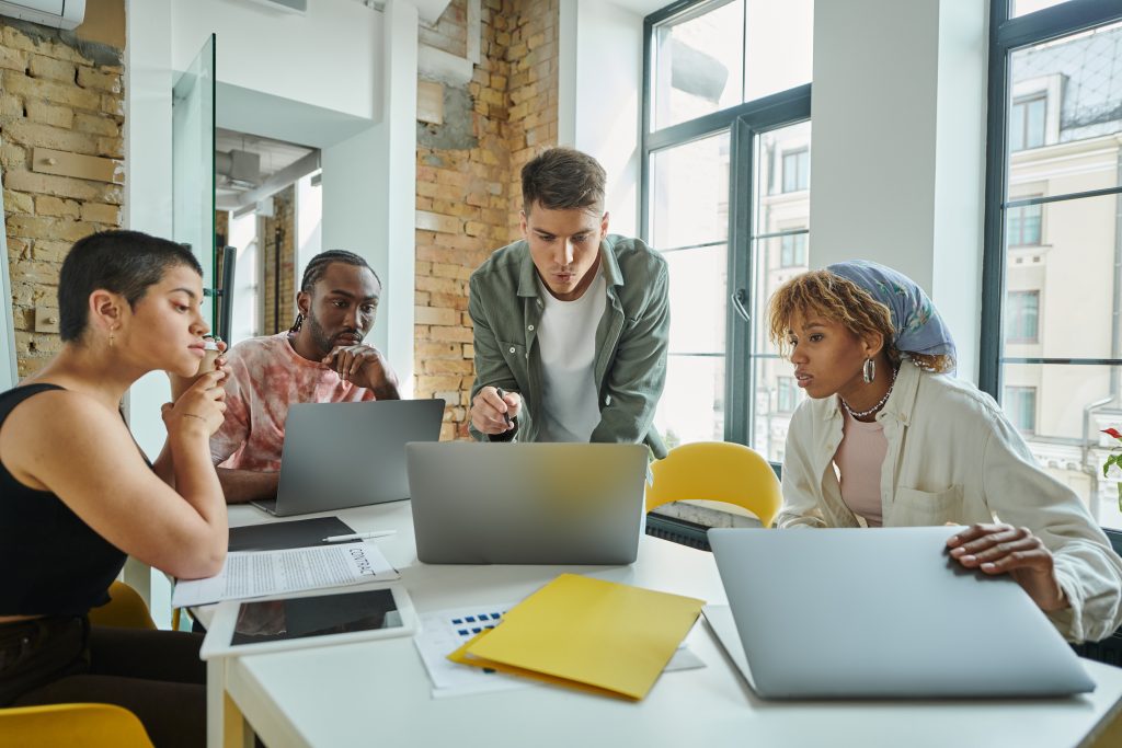 Pessoas conversam e acessam laptops em uma reunião de trabalho