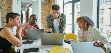 Pessoas conversam e acessam laptops em uma reunião de trabalho