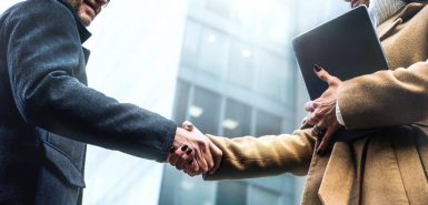 Imagem de um aperto de mãos entre um executivo homem branco e uma executiva mulher negra para ilustrar artigo de blog sobre o signo de Libra, conhecido pela sua diplomacia