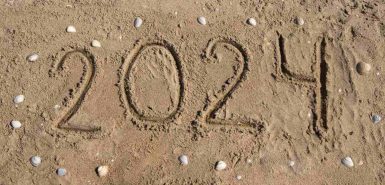 Desenho dos números do ano 2024 na areia da praia, com algumas conchinhas ao redor, para ilustrar conteúdo sobre Áries em 2024, previsões da astrologia