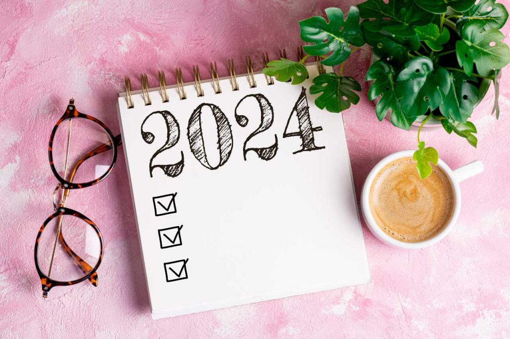 Lista de resoluções de 2024 com caderno, xícara de café na mesa, para ilustrar o Calendário Astrológico 2024