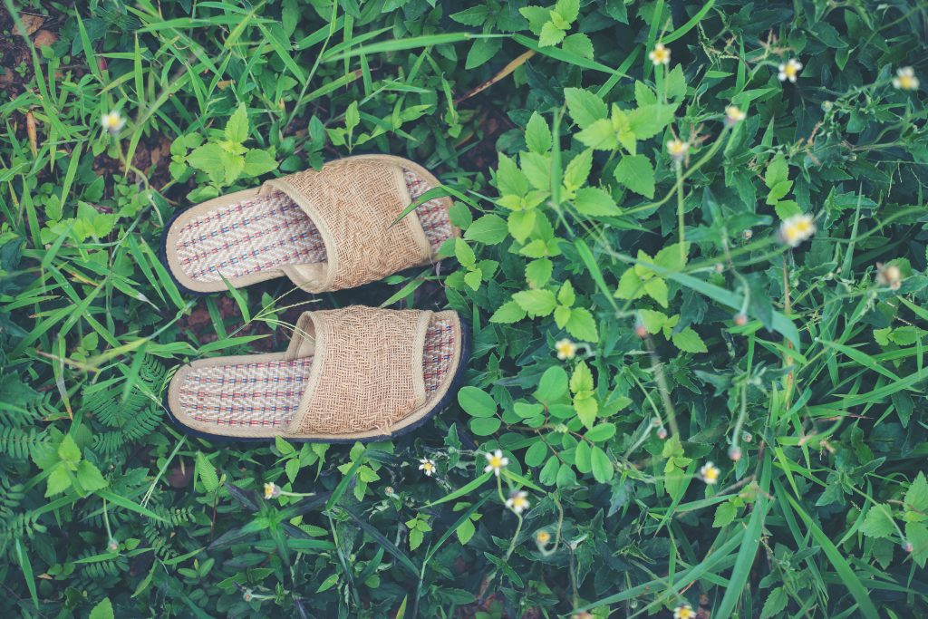 Chinelos muito confortáveis, sozinhos, sobre a grama verde, inspirando o conceito de relaxamento, para ilustrar notícia sobre equilíbrio entre vida pessoal e profissional