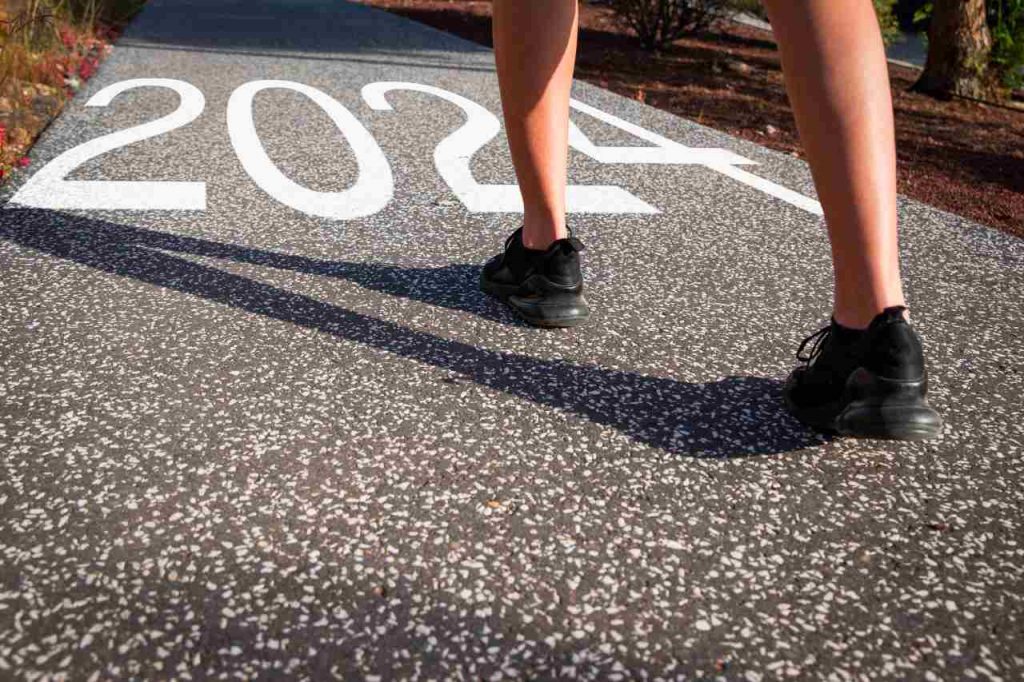 um pessoa corredora prestes a ultrapassar a escrita do número 2024, para o mapa do ano 2024