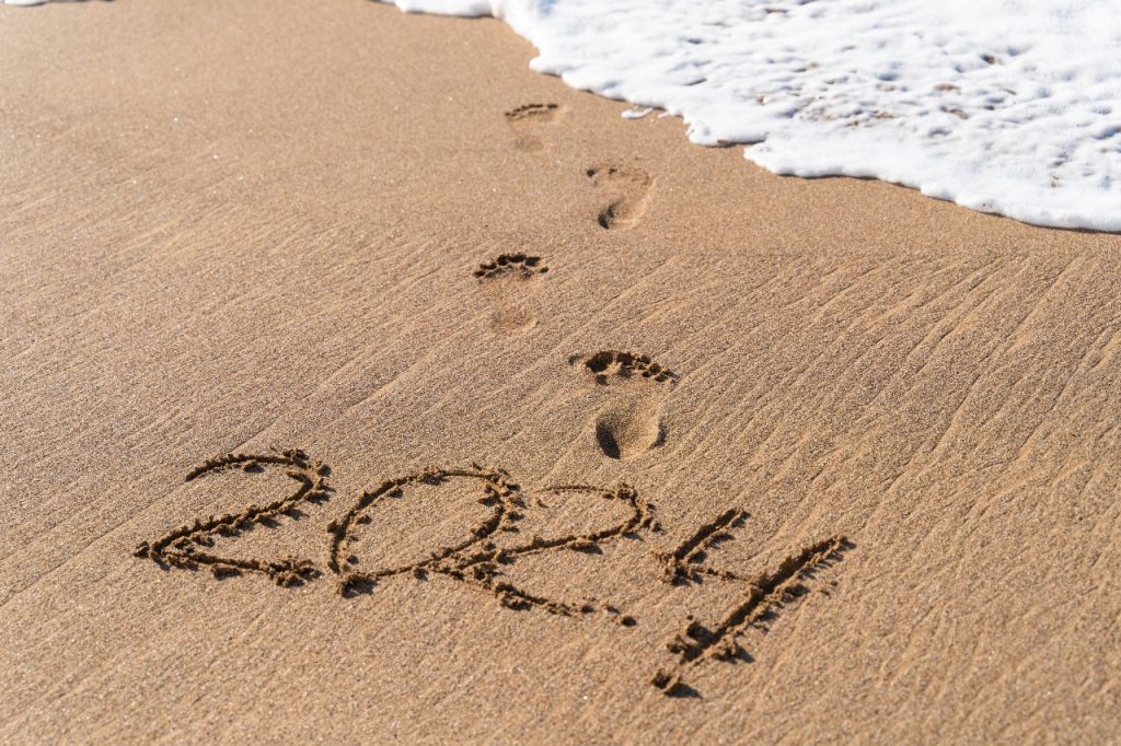 Escrita do ano "2024" na areia de uma praia, para ilustrar artigo de previsões de 2024 para cada signo