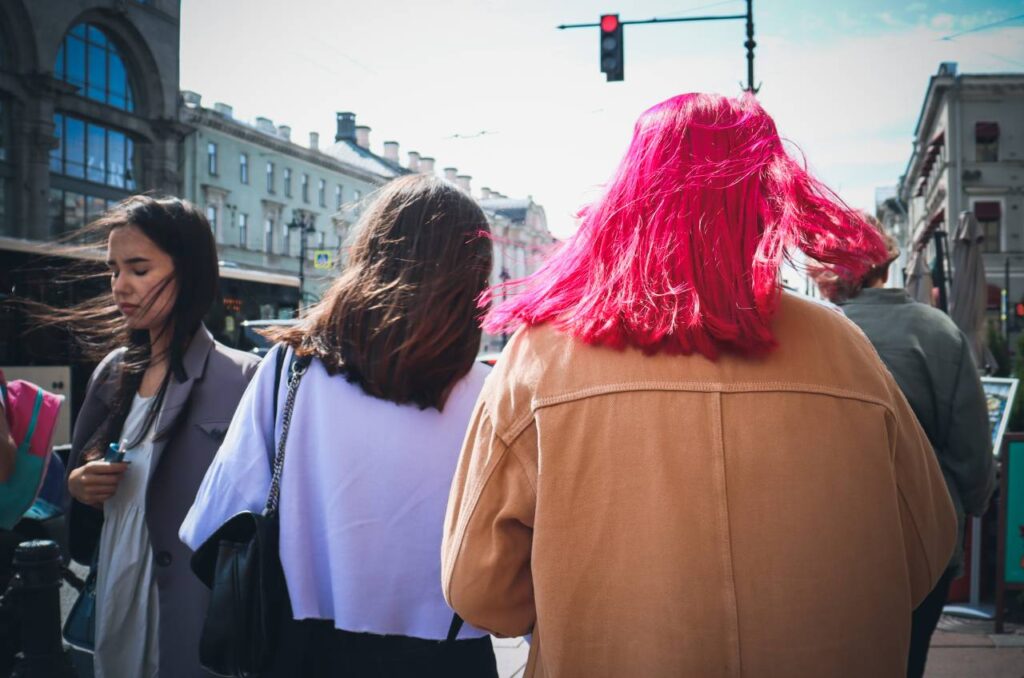 o cabelo vermelho de uma mulher de costas se destaca entre outras pessoas caminhando em ambiente urbano, para o horóscopo de fevereiro de 2024