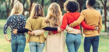 vista traseira de amigos se abraçando em um parque para ilustrar artigo sobre a temporada de aquário