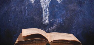 Signo do zodíaco Áries em um quadro-negro acima de livro antigo, para ilustrar artigo sobre o mito de áries