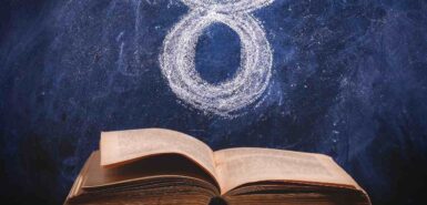 Símbolo do signo de Touro desenhado em giz em um quadro negro e um livro antigo aberto para ilustrar artigo sobre o mito de touro