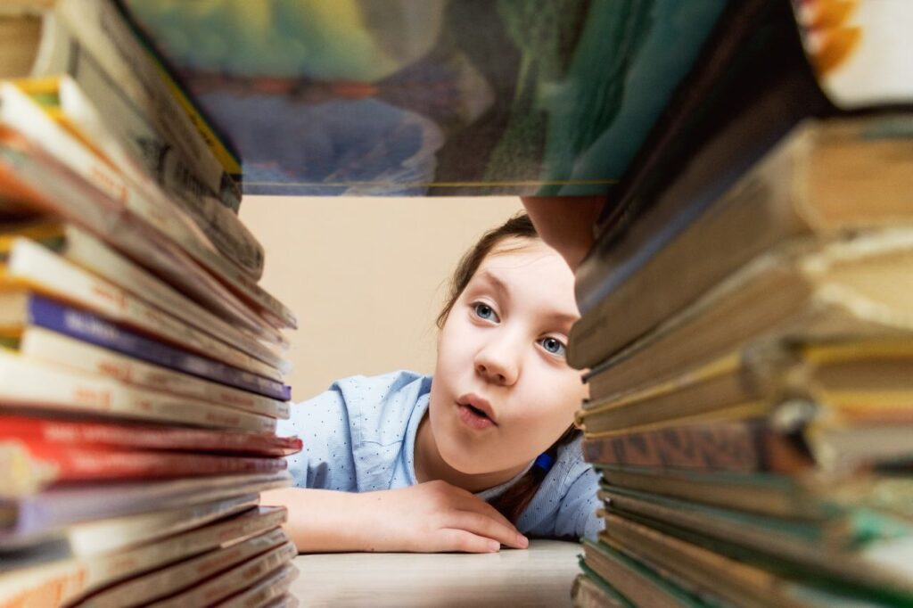 menina com interesse e curiosidade examina pilhas de livros, imagem para ilustrar artigo com dicas para o sol em Gêmeos