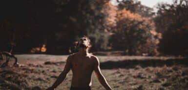 Homem espanhol de braços abertos sem camisa olhando para cima em uma floresta, para artigo que responde a pergunta se o ascendente fica mais forte depois dos 30