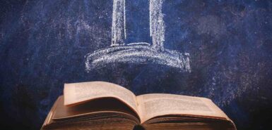 Signo do zodíaco Gêmeos desenhado a giz em um quadro-negro acima de livro antigo, para ilustrar artigo sobre o mito de gêmeos