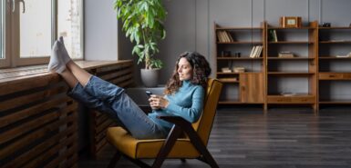 Mulher feliz relaxa em uma confortável poltrona em casa, para ilustrar artigo sobre a temporada de câncer para pessoas de todos os signos