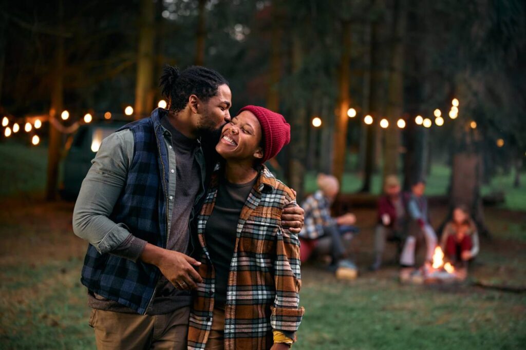 Casal afetuoso curtindo acampar na floresta, ilustrando notícia de que vênus está em câncer e o impacto desse trânsito