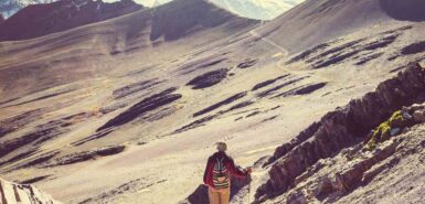 Uma pessoa em um passeio ou escalada pela montanha, ilustrando artigo de astrologia sobre realização profissional e vocação