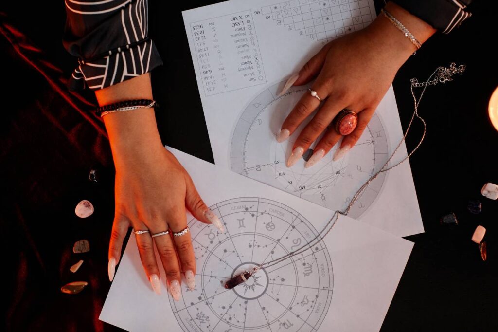 Mãos de uma mulher seguram duas cartas astrológicas, ilustrando artigo sobre como funciona a astrologia