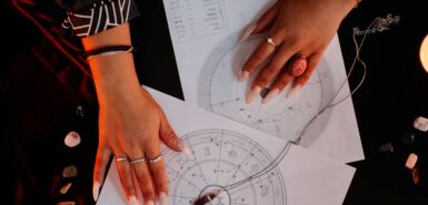 Mãos de uma mulher seguram duas cartas astrológicas, ilustrando artigo sobre como funciona a astrologia