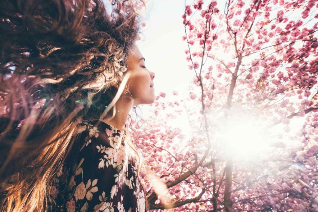 Mulher com semblante renovado em meio à vegetação da primavera