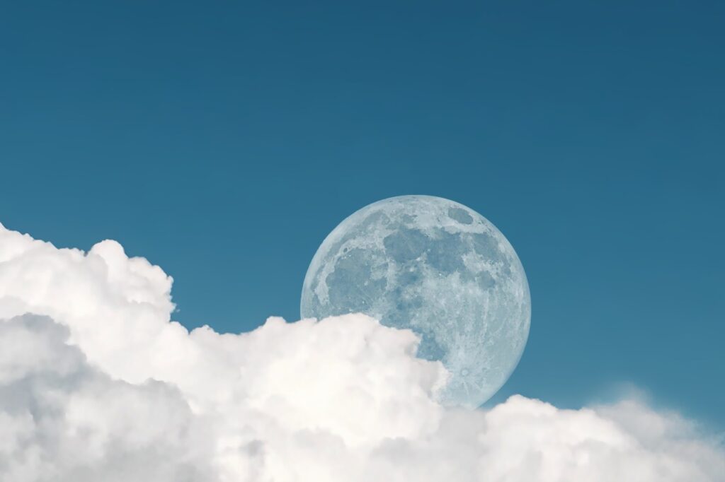 A Lua na fase cheia, com uma parte encoberta por nuvens brancas