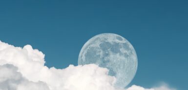 A Lua na fase cheia, com uma parte encoberta por nuvens brancas