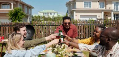 Grupo de jovens amigos inter-raciais tilintando com vinho e cerveja em festa ao ar livre