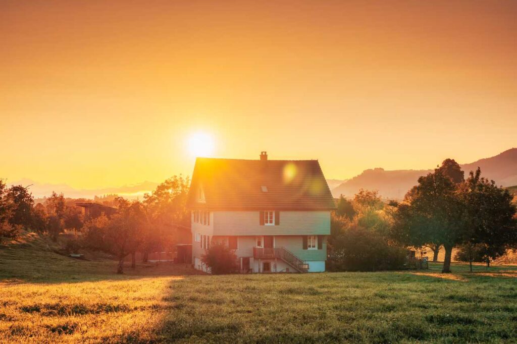 Nascer do sol brilhando sobre uma casa grande na colina entre o jardim no campo na Suíça