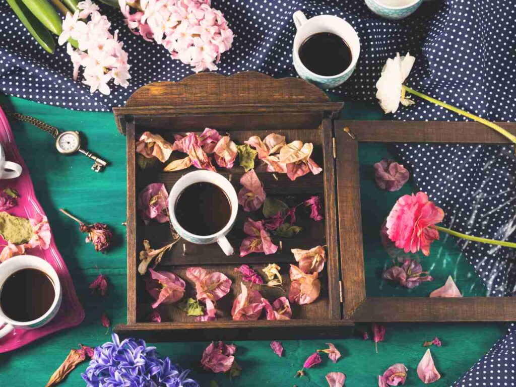 xícaras de café em bandejas sob uma mesa com tecidos e flores e pétalas