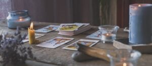 Cartas de tarô em uma mesa à luz de velas, com ervas e palo santo