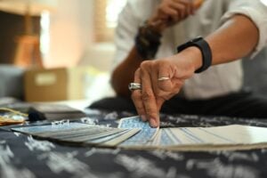 Mão com anéis escolhe uma carta em um baralho de tarot