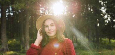 mulher com chapéu de palha em frente na contra luz do sol em um espaço de floresta