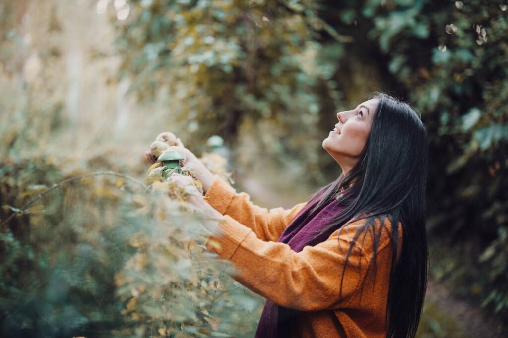 Mulher olhando através da cerca de metal na floresta