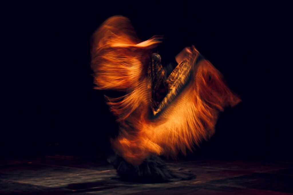 Dançarina de flamenco em traje tradicional com xale motion blur. Dança espanhola flamenca no palco