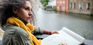 Artista mulher madura fazendo um desenho em um bloco de papel sobre um canal em Londres
