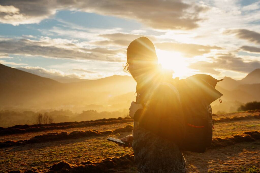 homem mochileiro com a luz do sol em um ambiente de montanha