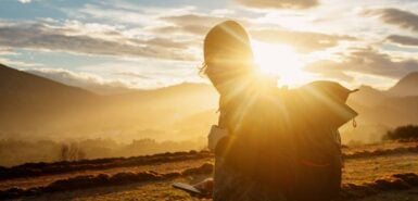 homem mochileiro com a luz do sol em um ambiente de montanha