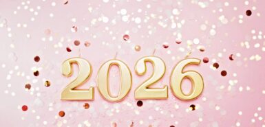 Números do ano de 2026 feitos por velas douradas sobre fundo rosa de glitter.