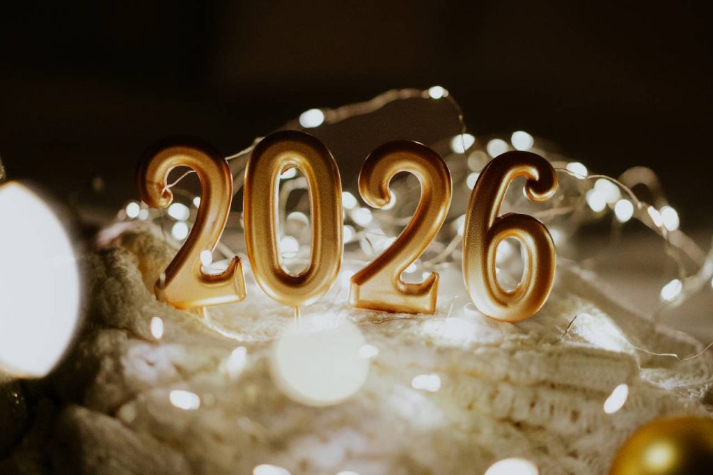 Um bebê recém-nascido deitado em um cobertor, com números dourados que formam o ano de 2026