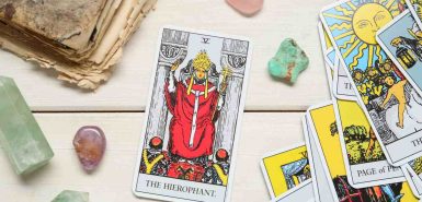 Composição plana com Hierofante e outras cartas de arcanos de tarot na mesa de madeira, junto com quartzo rosa e outros cristais