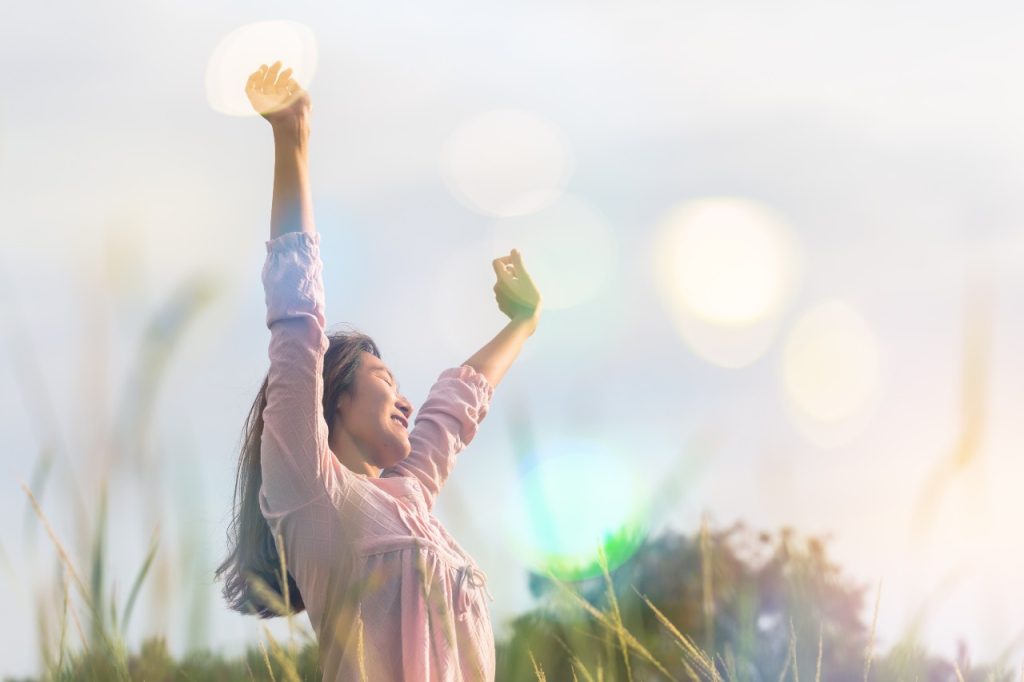Jovem em pé em pose de relaxamento ou pose de liberdade ou pose relaxante no prado durante o nascer do sol