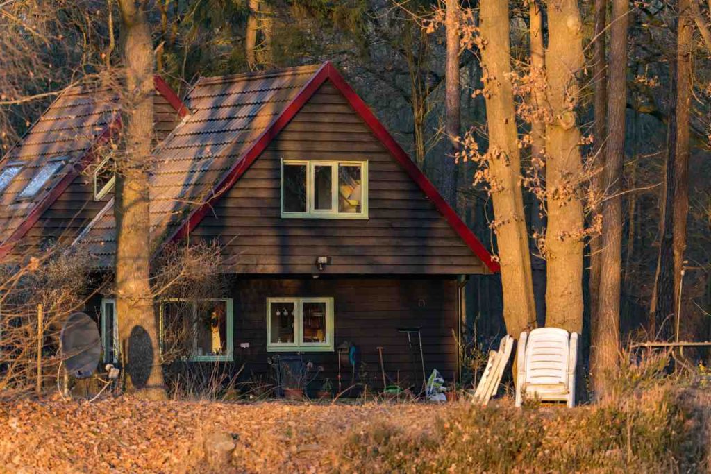 Casa recreativa de madeira na floresta iluminada pela baixa luz solar. Ângulo traseiro. Gelderland. Os Países Baixos