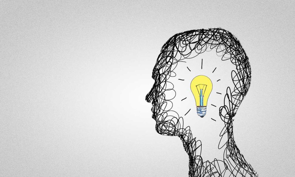 Silheta da cabeça de um homem em desenho com caneta preta e, dentro dele, o desenho de uma lâmpada amarela acesa