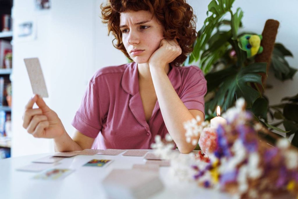 jovem ruiva sentada à mesa em casa, colocando cartas tarot para leitura