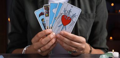 Cartomante com cartas de tarô na mesa cinza dentro de casa, closeup