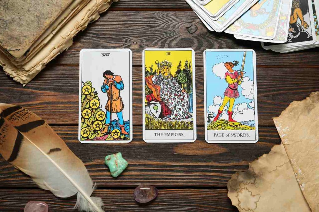 Cartas de tarot, livro antigo, cristais e penas na mesa de madeira, posição plana